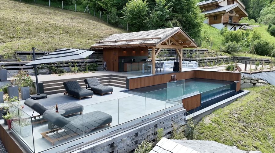 Infinity pool and wooden pavilion on an alpine hillside